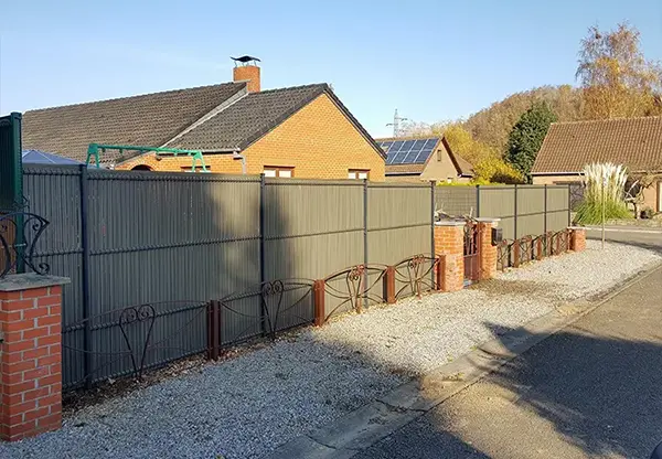 Une barrière brise-vue est installée devant une maison, créant une séparation visuelle et un espace privé.