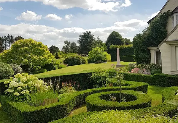Jardin soigné avec maison en arrière plan, mettant en valeur des formes élégantes et un décor magnifique.