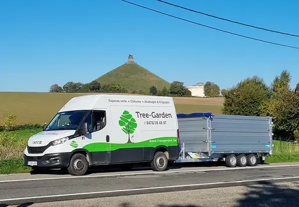 Camionnette blanche de Tree-Garden avec remorque sur le bord de la route, utilisée pour les services d'aménagement extérieur de jardin, d'entretien, ...